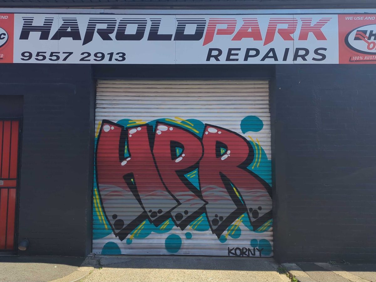 The Harold Park Repairs workshop roller door, painted with a large red and teal HPR mural, under the black shopfront sign
